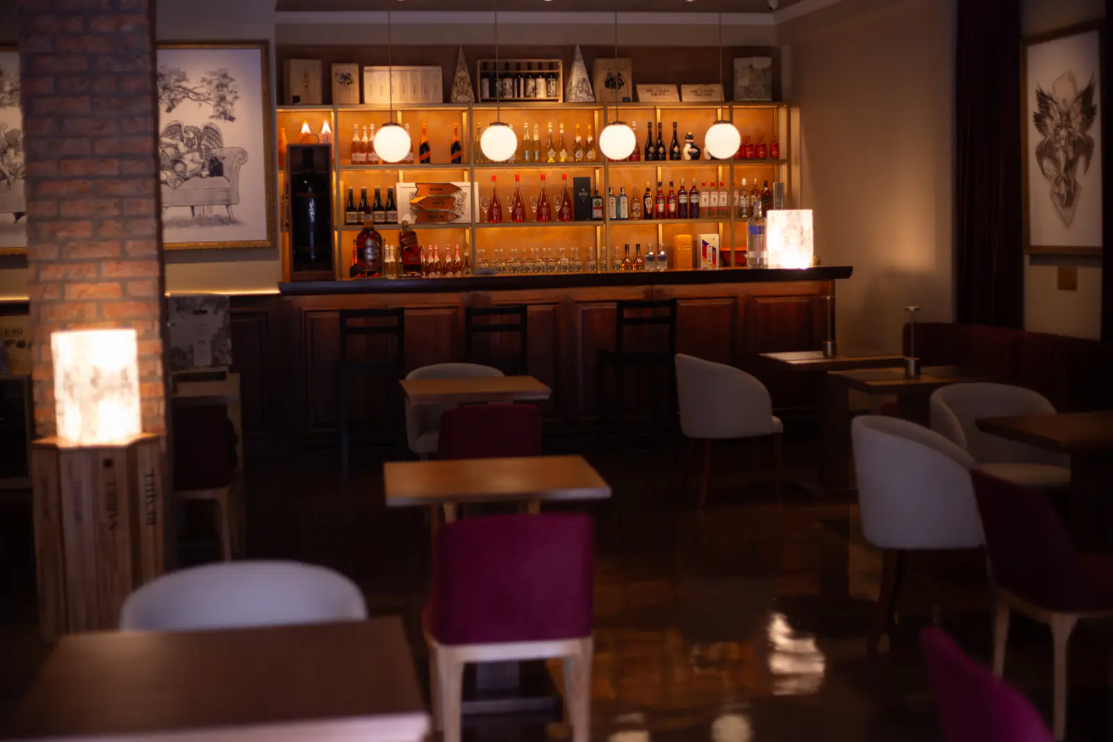 Salón con barra de tragos iluminada, lámparas globo y sillones de terciopelo